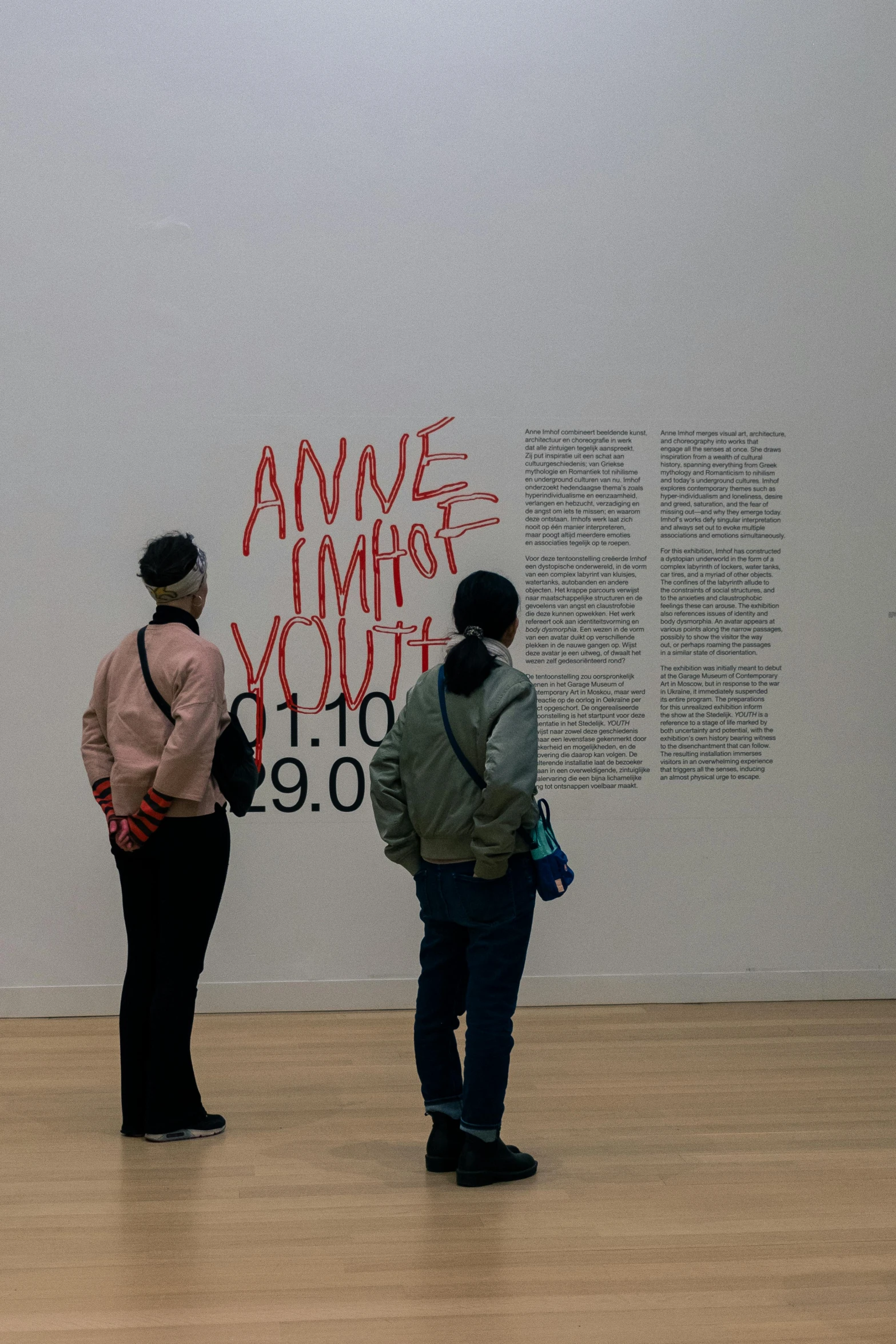 people in a museum are standing next to each other and some words on the wall behind them