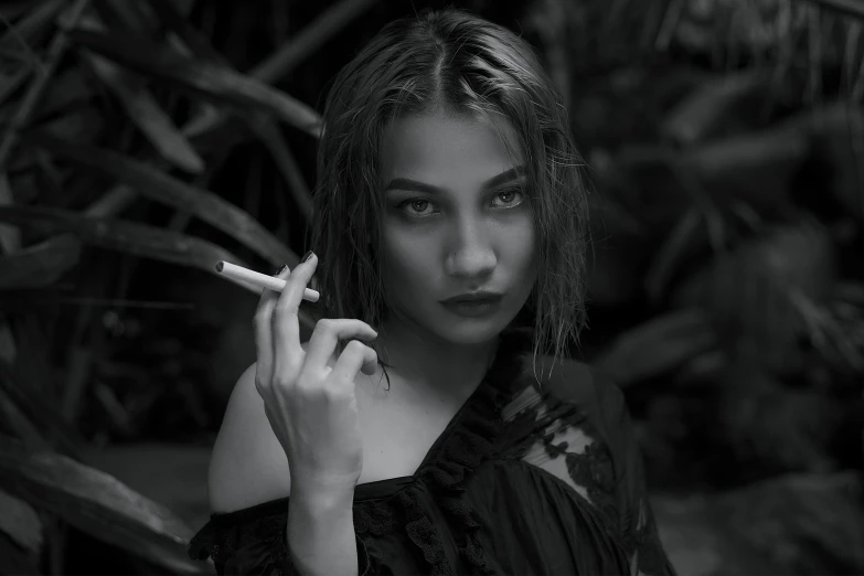 the woman is smoking the cigarette near some plants