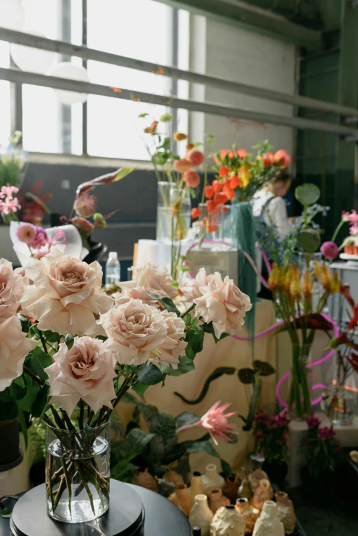 a large vase of roses next to a pile of flowers