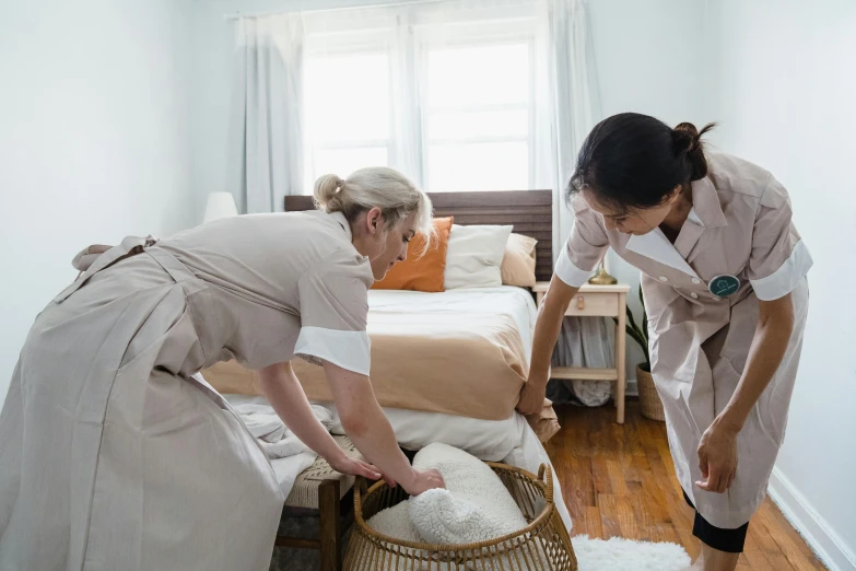 two women in robes clean a bed