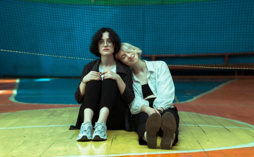 two people are sitting on the basketball court and one is holding their head