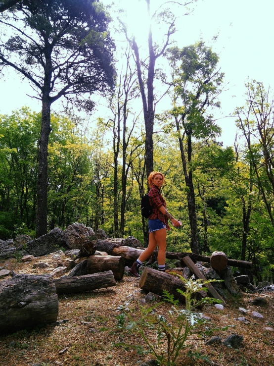 a woman with a backpack is walking in the woods