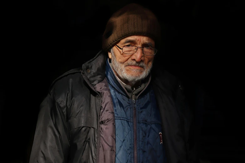 an older man in the dark wearing a jacket