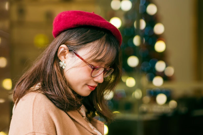 a woman wearing a red hat looks down at her cell phone