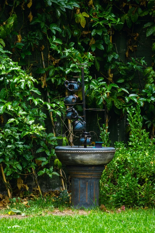 a statue of vases next to a bush with some green leaves on it