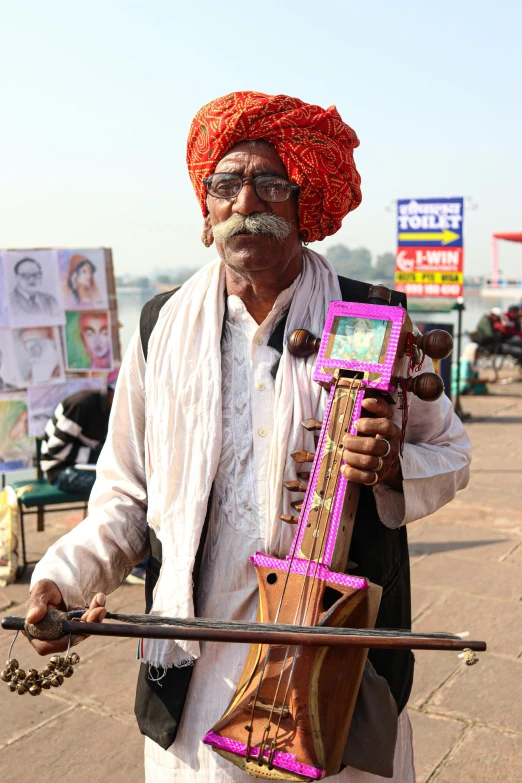 an old indian man is displaying a purple instrument