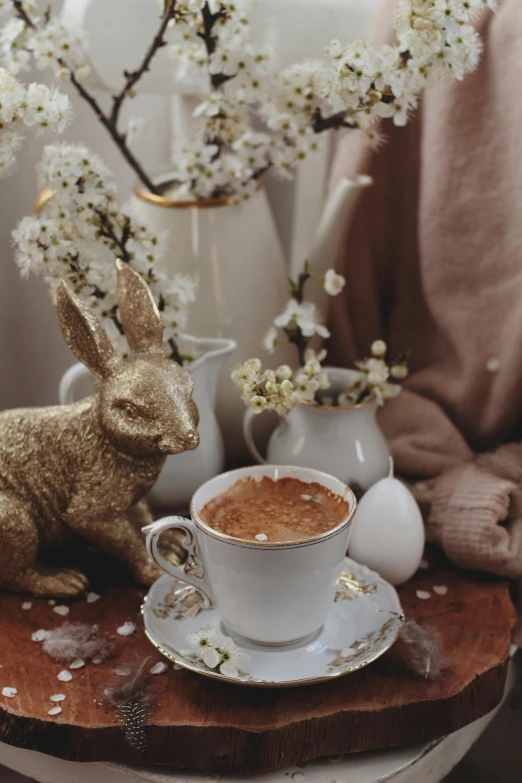 a coffee cup filled with liquid sits on a saucer beside a bunny figurine