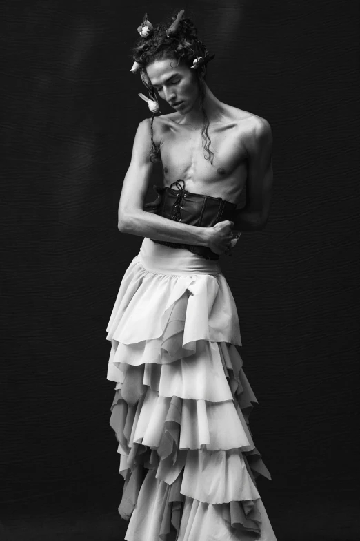 a person in a long dress standing up against a black background