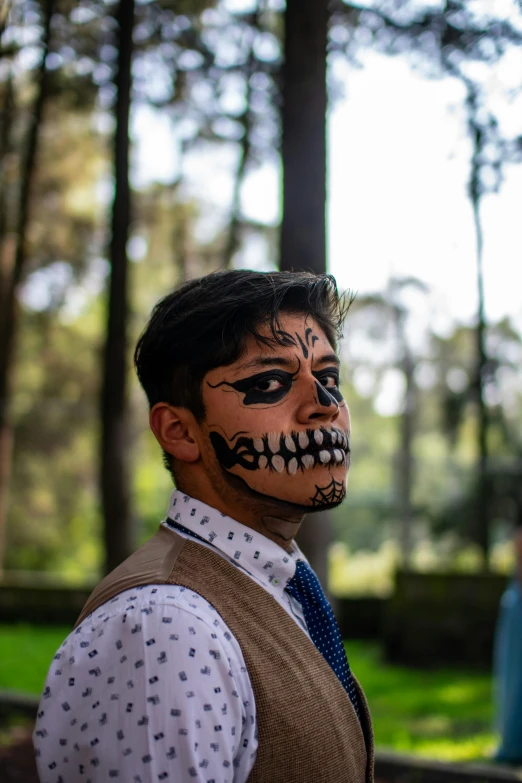 a man is standing in front of some trees with makeup