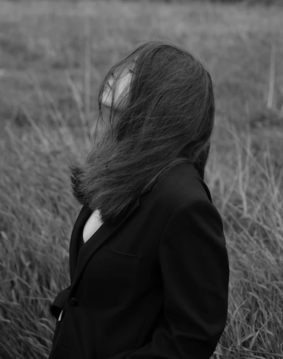 a woman with her back turned, walking through a field