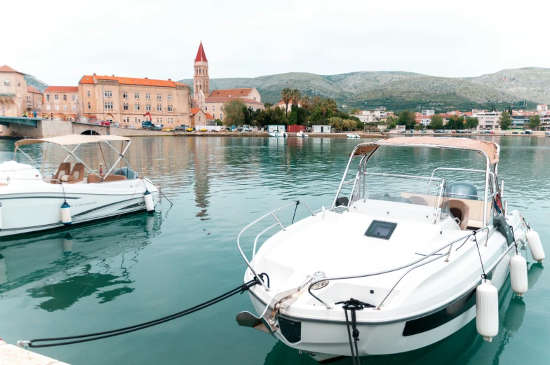 three white boats parked in the water by a city