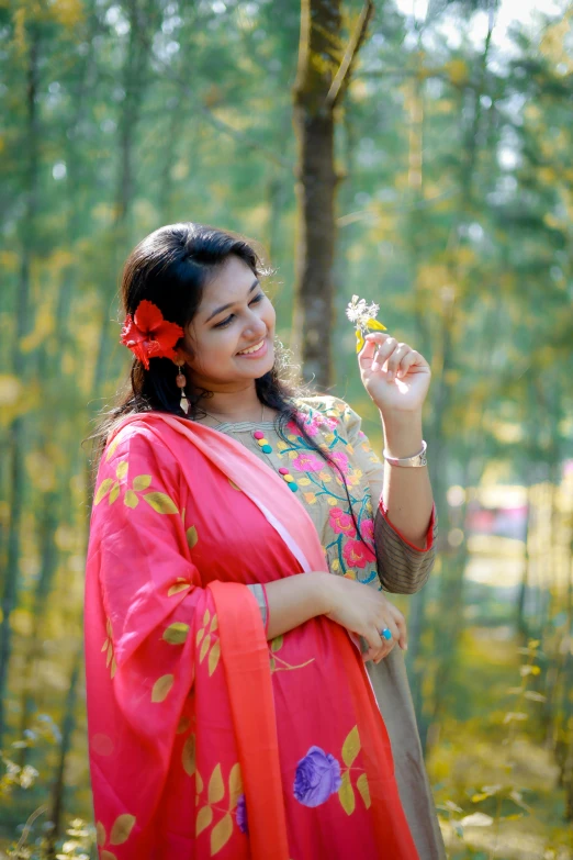 a beautiful woman holding a flower in the woods