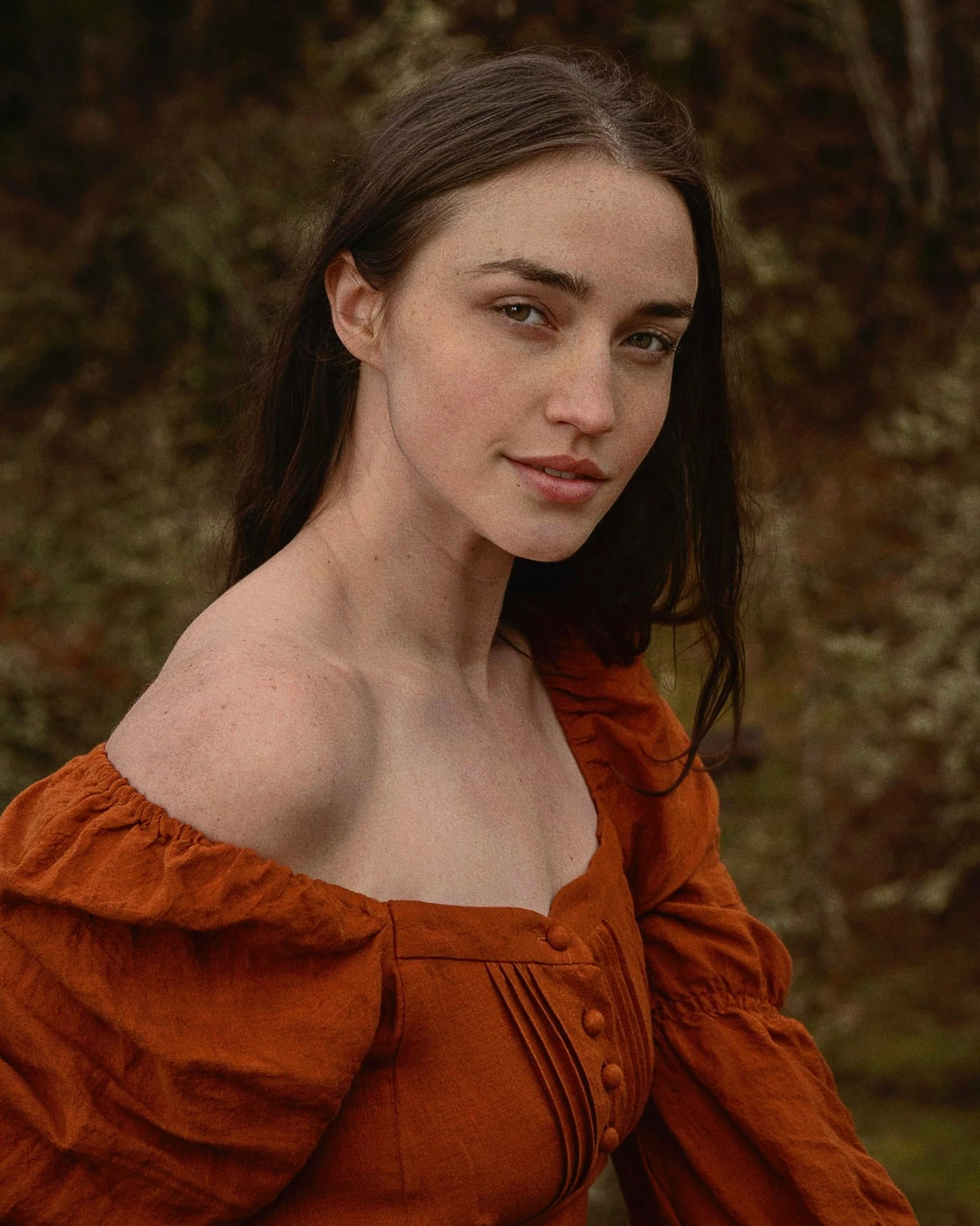 a beautiful young woman in an orange top looking into the camera