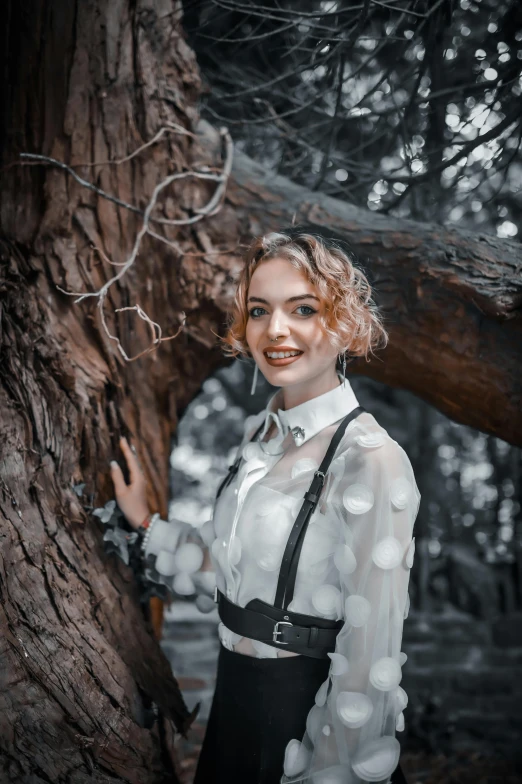 a young woman posing for a picture near a tree