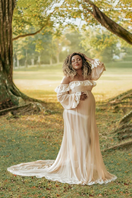 a pregnant woman is standing under a tree