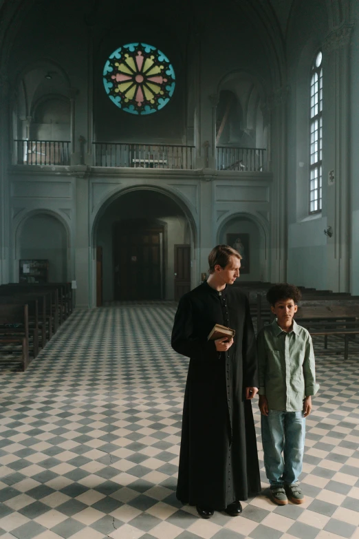 a woman standing next to a little boy in front of a stained glass window