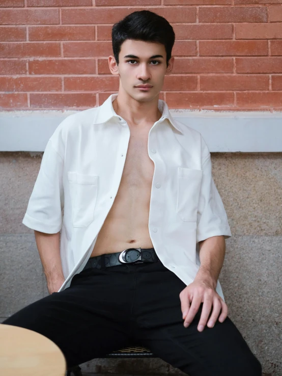 a shirtless male sitting on top of a stool