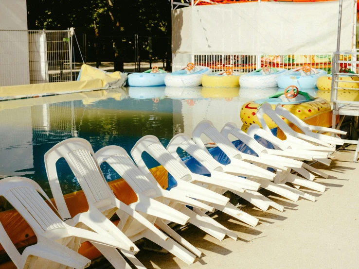 a row of white chairs next to an empty pool