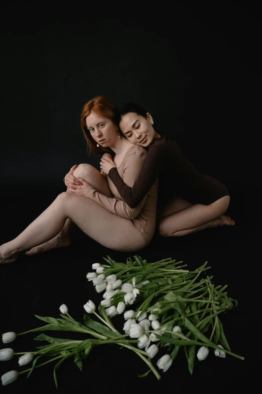 a woman in tights holds another woman on her back while surrounded by flowers