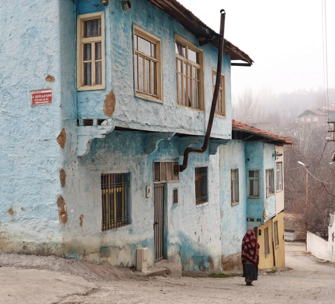 a woman in red stands outside a blue building
