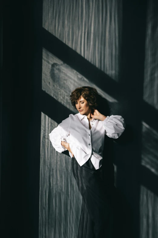 woman in dress shirt and skirt with shadows coming through wall