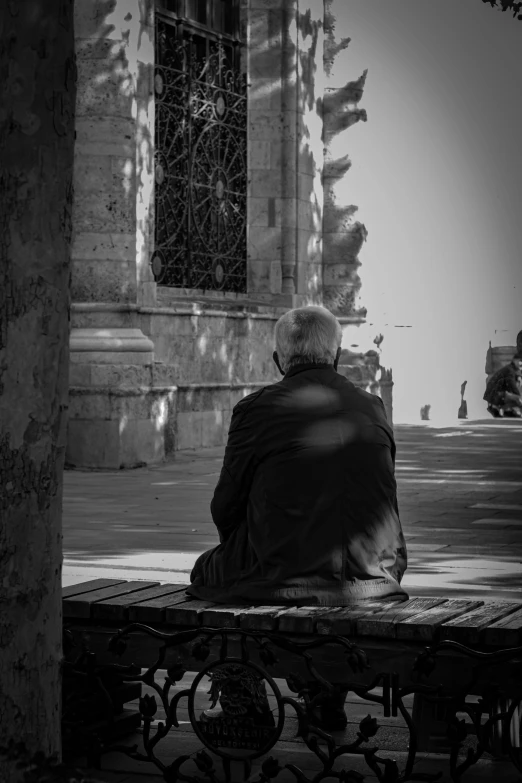 a man sitting alone on top of a bench