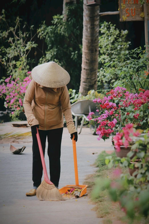 a lady sweeping the sidewalk with a broom and sweeper