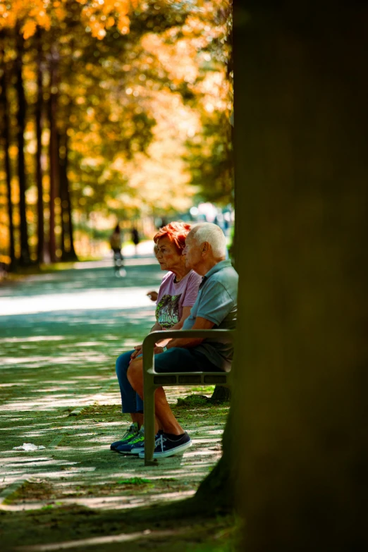 two elderly people sitting on a bench in the park