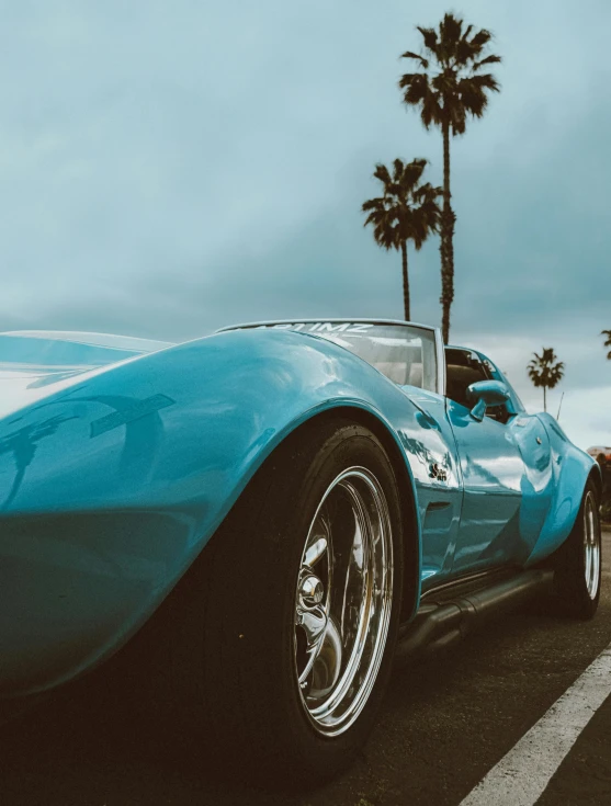 an old car with some palm trees and blue sky