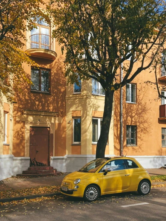 a yellow car sitting in the front of a tall orange building