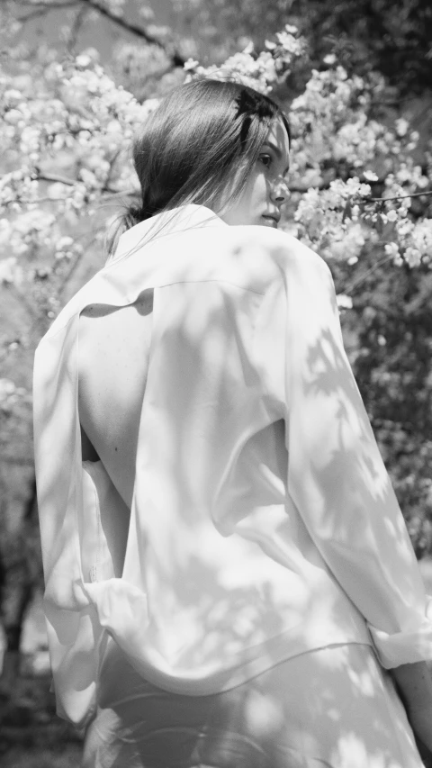 a woman walking through the park wearing a dress