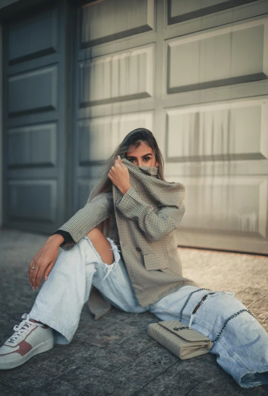 a man sitting on the ground wearing ripped jeans