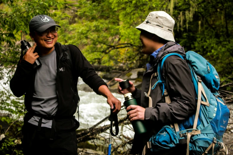 two men hike through a river carrying hiking gear