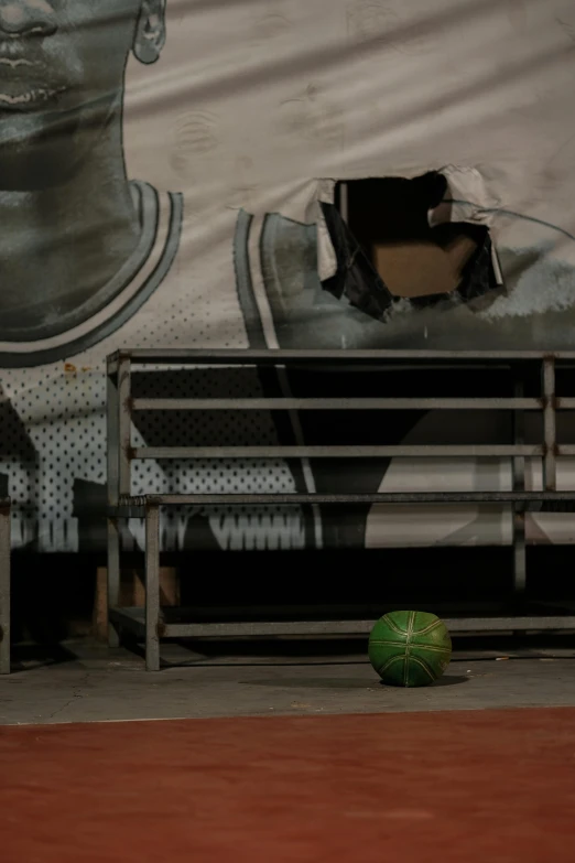 a tennis ball on a wooden floor in front of a wall with the image of a woman