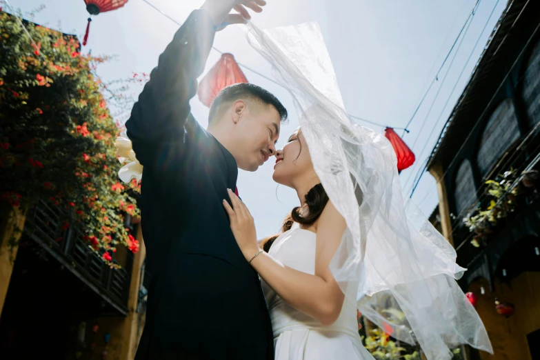 a bride and groom stand together in front of a building with flowers