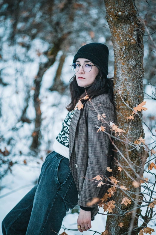 a person leaning against a tree in the snow