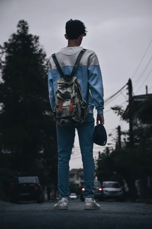 the back view of a person walking down the street wearing a backpack