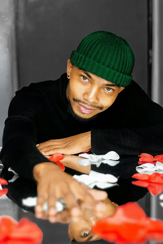 a man wearing a green knit hat at a table with flowers on it