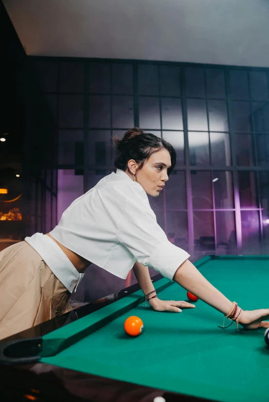 a young lady is playing pool at a bar