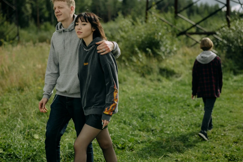 a man and woman in a field standing by each other