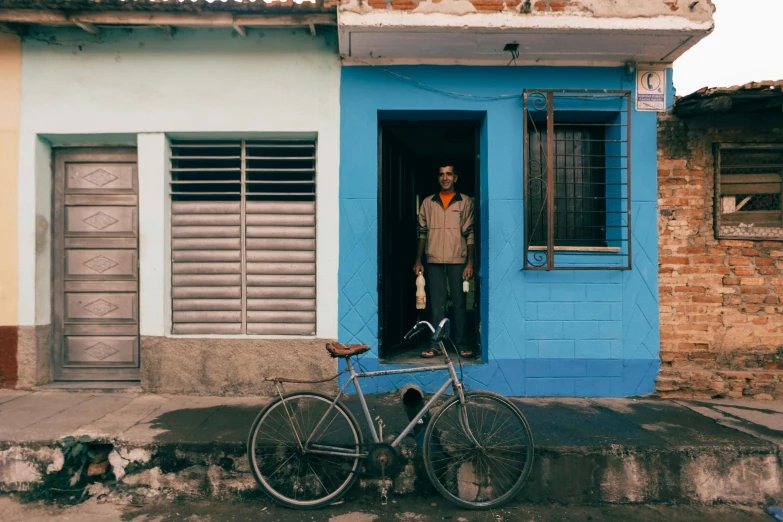 a man in an over sized hat standing behind a bike with the doors open