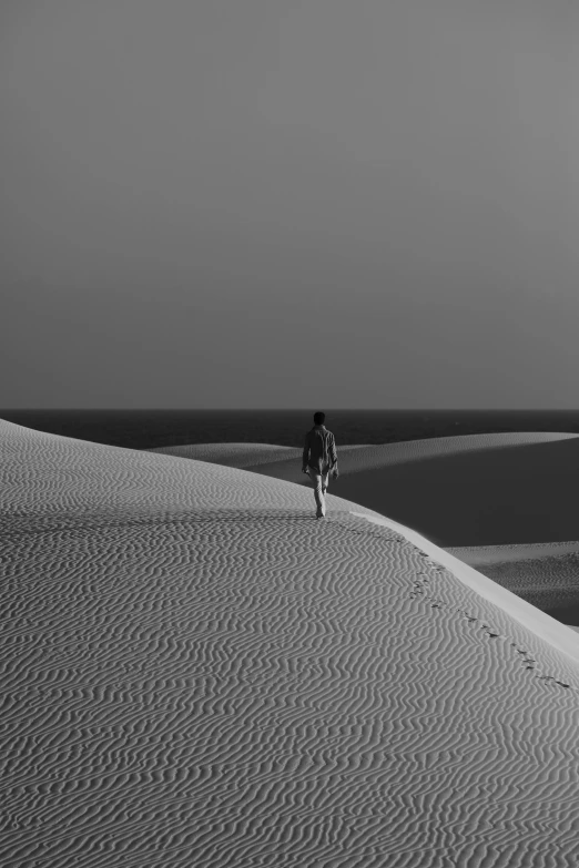 the lone person is walking on sand dunes