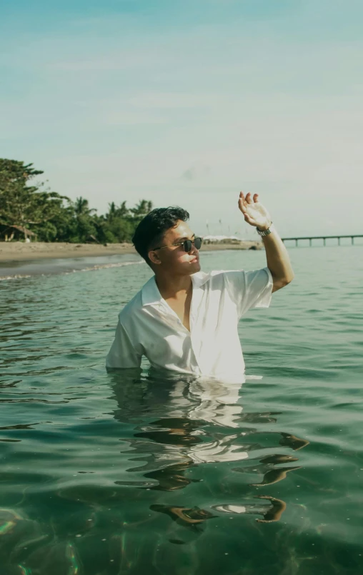 man in white shirt and black sunglasses standing in water