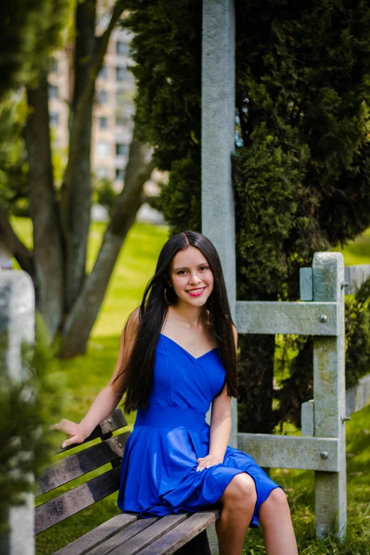 a woman in a blue dress is sitting on a bench