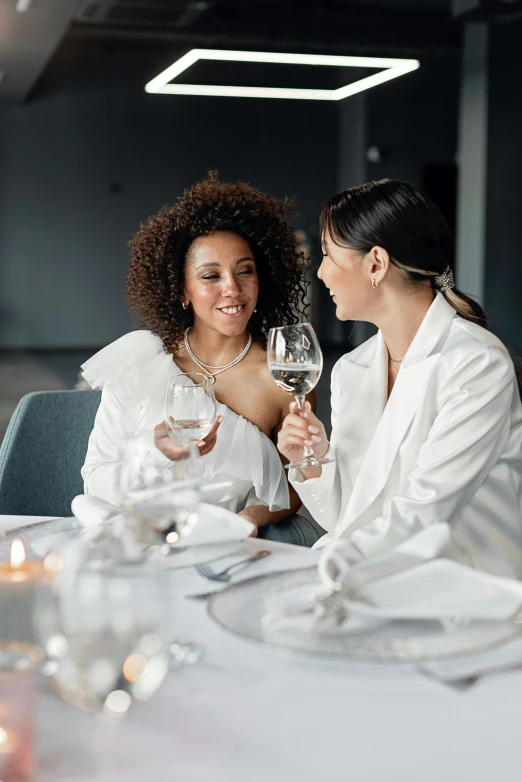 two women sitting at a table drinking some wine