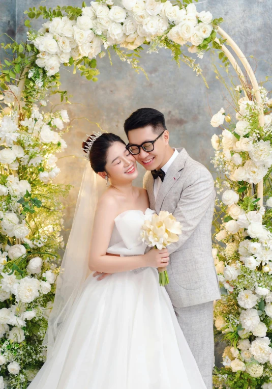 a couple is posing in front of a flower arch