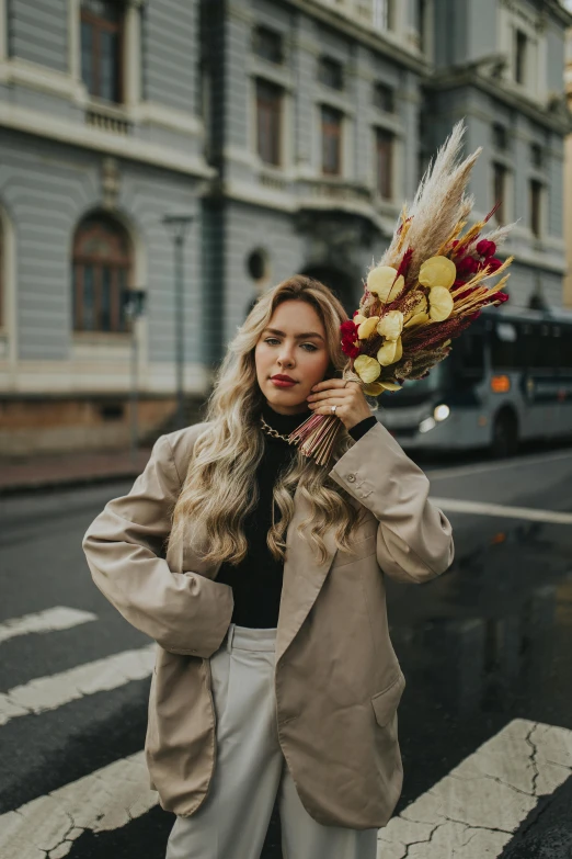 a woman in a beige jacket holding a bunch of flowers