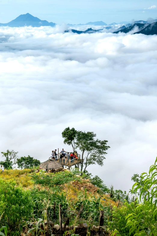 some people sitting on top of a hill looking at the clouds