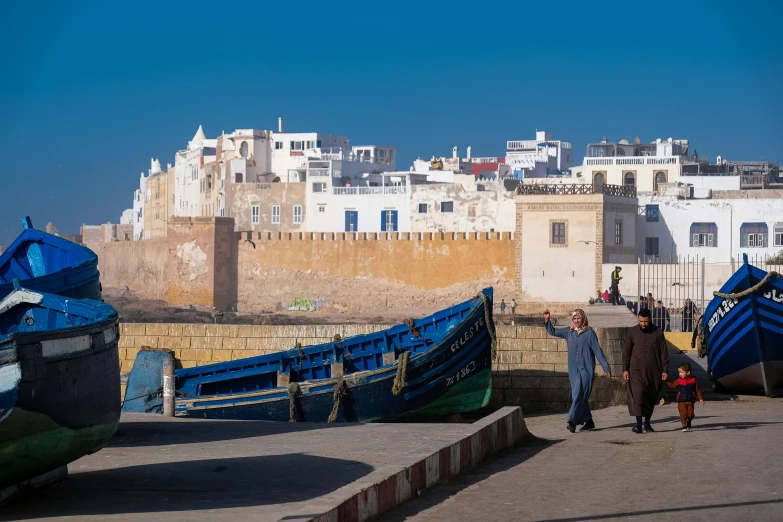 a woman walking towards boats by a seafront