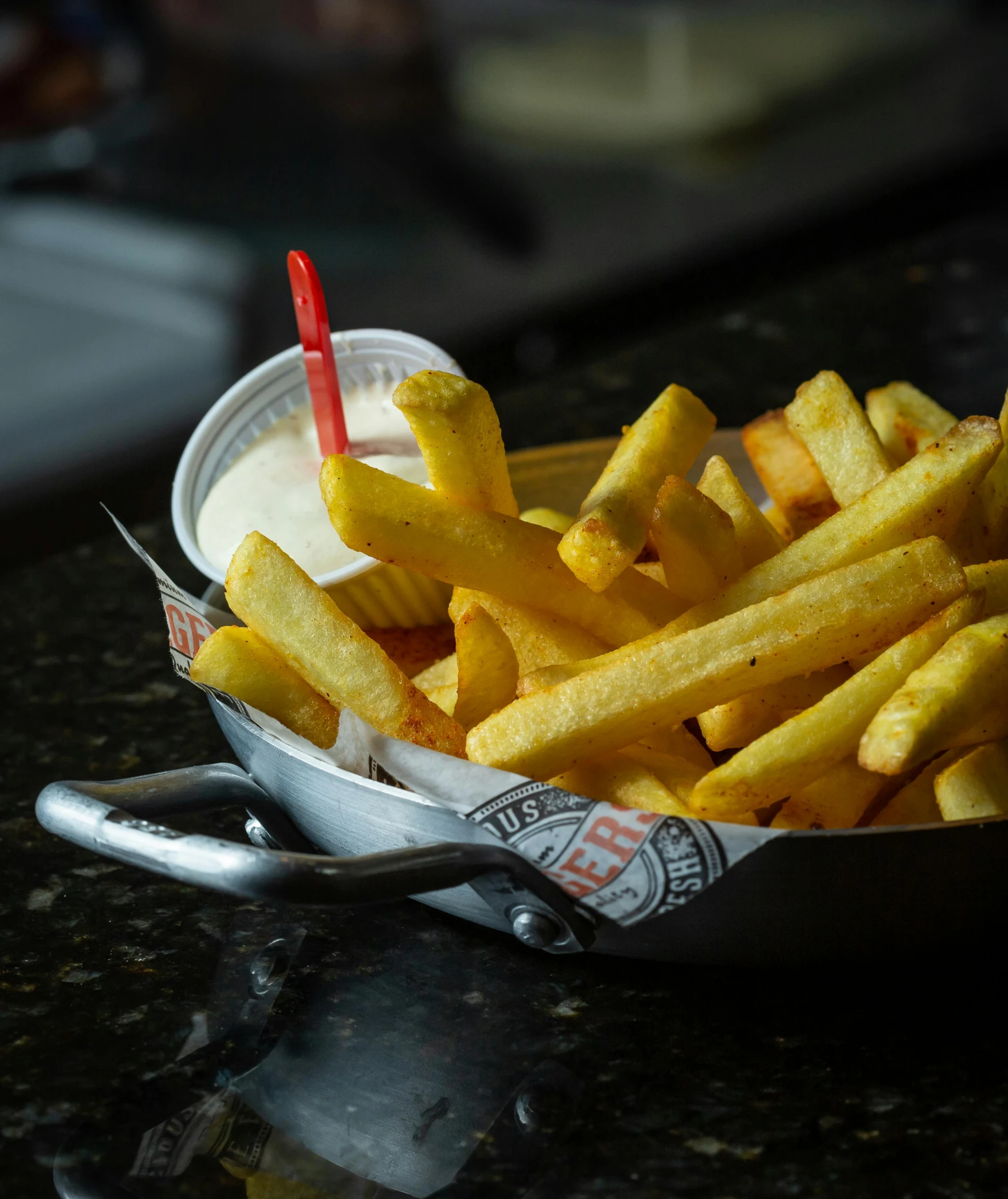 a close up of french fries in a basket with dipping sauce